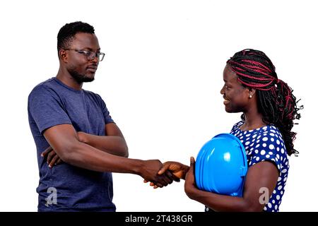 young man shaking hands with young female construction engineer while smiling. Stock Photo