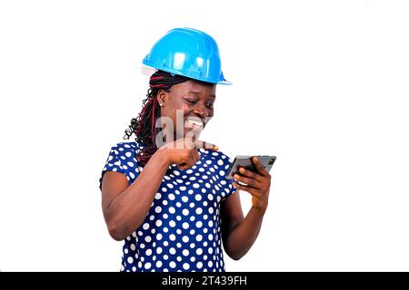 young female engineer wearing blue safety helmet pointing finger at mobile phone screen while watching videos. Stock Photo