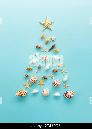 A Christmas tree made of shells and starfish is laid out on a blue background. High quality photo Stock Photo