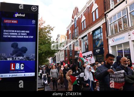 Leicester, Leicestershire, UK. 28th October 2023. Protesters march past a news report on an advertising screen during a pro-Palestinian demonstration. Tens of thousands of pro-Palestinian protesters have gathered in London and across the UK for rallies urging an end to Israel's attacks in Gaza. Credit Darren Staples/Alamy Live News. Stock Photo