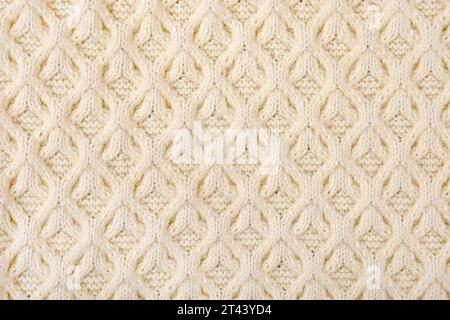 Knitted beige background. Large knitted fabric with a pattern. Close-up of a knitted blanket Stock Photo