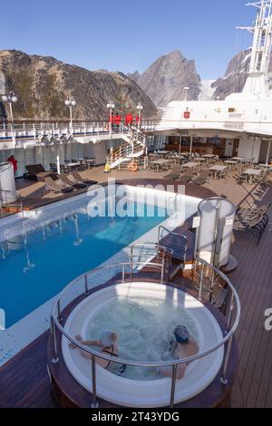 Greenland tourism; tourist couple enjoying the Jacuzzi on an arctic cruise, cruising with Silversea cruise Line on the Silver Cloud ship, Greenland. Stock Photo