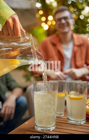 Friends at table with fresh lemonade having fun at outdoor picnic Stock Photo
