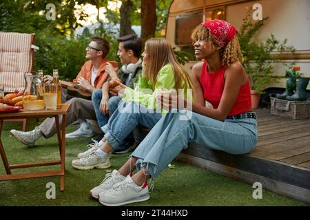 Happy group of friend sitting in row eating snacks rest during picnic Stock Photo