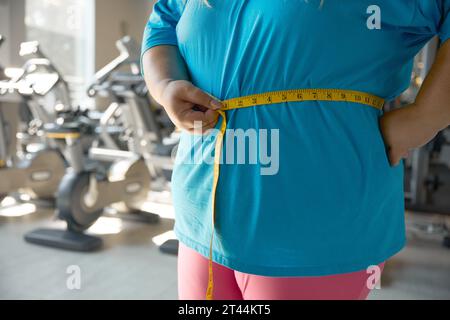 Closeup waistline of overweight woman wrapped in measuring tape Stock Photo