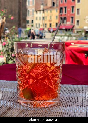 aperol cocktail, side view aperol spritz glass on table with over buildings and street in Venice, Italy. traditional Italian local spritz cocktail on Stock Photo