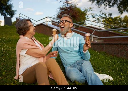 Happy joyful senior couple eating ice-cream in park Stock Photo