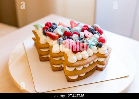 The christmas tree-shaped layer cake is decorated with fresh berries, chocolate and flowers. The cake with cheese cream and honey cakes.Cake with Stock Photo