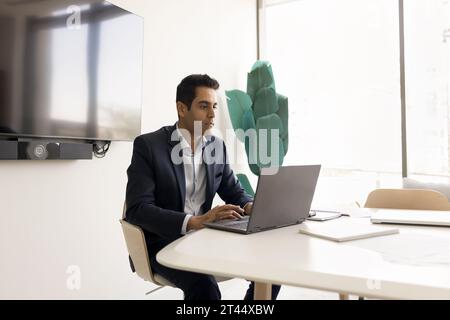 Focused handsome Indian businessman working at laptop Stock Photo