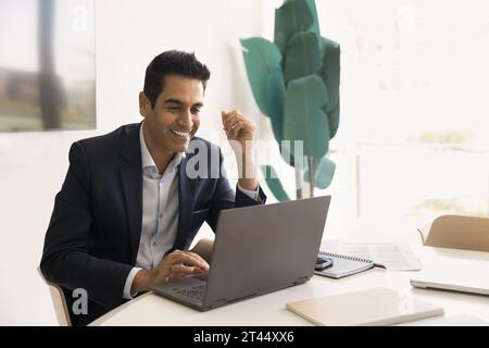Happy successful Indian businessman using Internet service on laptop Stock Photo