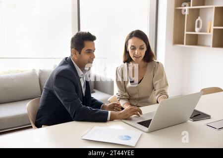 Couple of focused busy multiethnic professionals working at laptop together Stock Photo