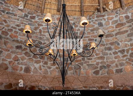 forged iron chandelier in a room with stone walls and thatched roof, vintage style Stock Photo