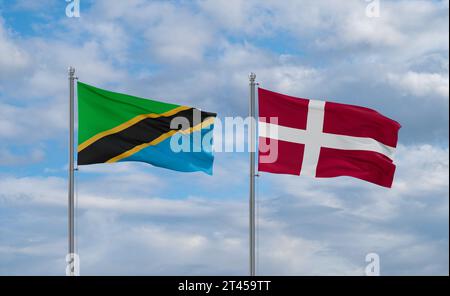 Tanzania and Denmark flags waving together in the wind on blue cloudy ...