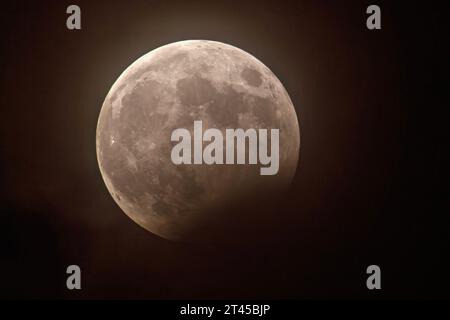 Partielle Mondfinsternis um 22:14 Uhr, Vollmond am Nachthimmel über München, 28. Oktober 2023 Deutschland, München, 28. Oktober 2023, partielle Mondfinsternis am Nachthimmel über München, um 22:14 Uhr hat sich der Kernschatten der Erde maximal über den Vollmond geschoben, eine kurze Wolkenlücke erlaubt den Blick auf das Himmelsspektakel, ein Teil des Mondes unten rechts ist angeknabbert, Nacht, nachts, *** Partial lunar eclipse at 22 14 oclock, full moon in the night sky over Munich, 28 October 2023 Germany, Munich, 28 October 2023, partial lunar eclipse in the night sky over Munich, at 22 14 Stock Photo