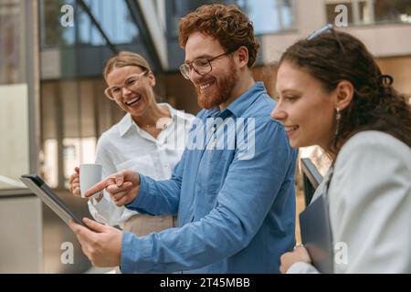 Businessman showing something on digital tablet to colleagues during working day outside of office Stock Photo