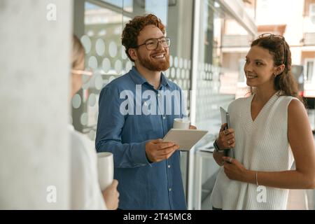 Business colleagues talking and laughing during break time in office background Stock Photo