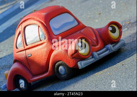Anthropomorphic red toy car traveling upward on an asphalt road Stock Photo