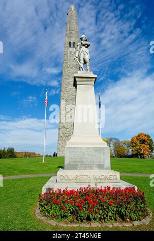 1911 granite statue of Colonel Seth Warner before stone obelisk under cloud swept blue sky commemorating the 1777 Battle of Bennington — October 2023 Stock Photo