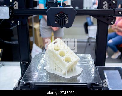 Prototype of car engine printed on 3D printer from molten white plastic on working surface 3D printer. Three-dimensional model. Additive progressive modeling technology. Modern new printing industry. Stock Photo