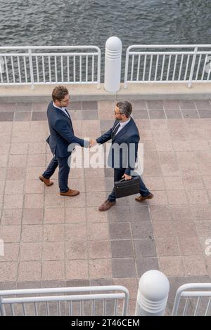 Handshake with partner in the city for greeting. Businessmen in suit shaking hands outdoors. Handshake between two businessmen. wo business men had Stock Photo