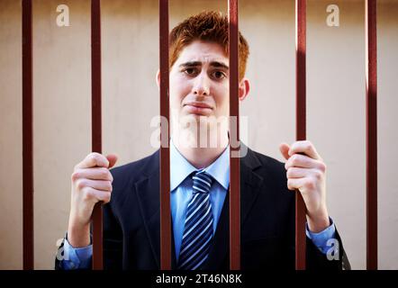 Portrait, crime and a business man in jail as a prisoner behind bars for white collar fraud, embezzlement or money laundering. Security, depression Stock Photo