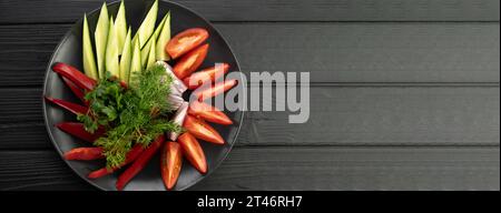 Platter of assorted fresh vegetables on black background. Banner. Stock Photo