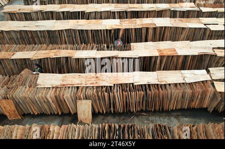 NEIJIANG, CHINA - OCTOBER 28, 2023 - An aerial photo shows a worker drying thin wood chips at a wood processing plant in Neijiang City, Sichuan Provin Stock Photo