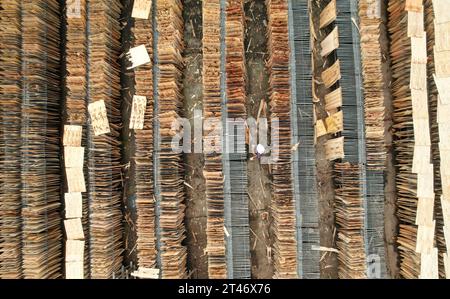 NEIJIANG, CHINA - OCTOBER 28, 2023 - An aerial photo shows a worker drying thin wood chips at a wood processing plant in Neijiang City, Sichuan Provin Stock Photo
