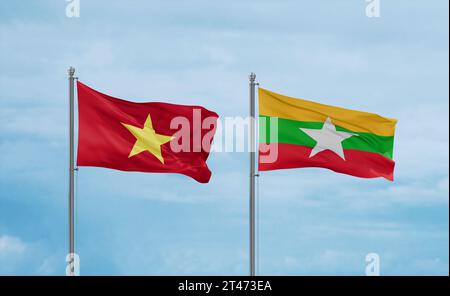 Myanmar aka Burma and Vietnam flags waving together on blue cloudy sky, two country relationship concept Stock Photo