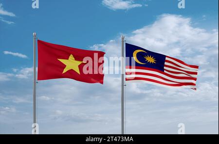 Malaysia and Vietnam flags waving together in the wind on blue cloudy sky, two country relationship concept Stock Photo