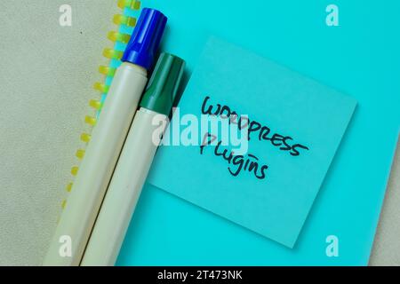 Concept of Wordpress Plugin write on sticky notes isolated on Wooden Table. Stock Photo