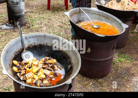 Cooking appetizing traditional fast food in a large cauldrons outdoors during the ethnic holiday Stock Photo