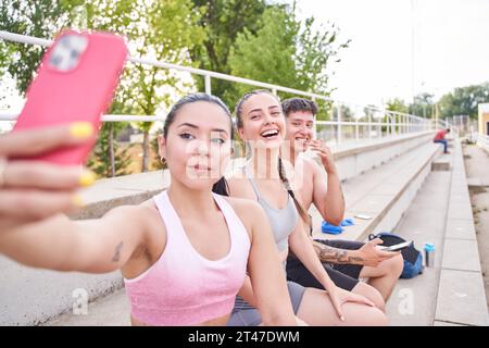 Portrait of three sporty young people after running outdoors making selfie. Stock Photo