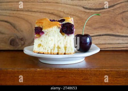 Cherry cake on white plate and wooden background. Selective focus. Stock Photo