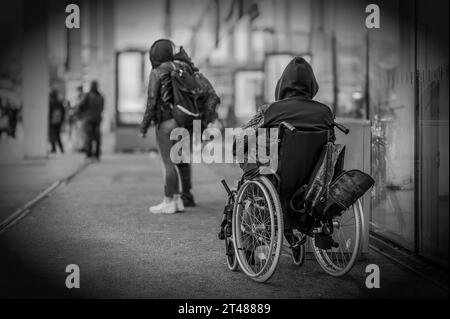 A homeless man in a wheelchair in front of a public building Stock Photo