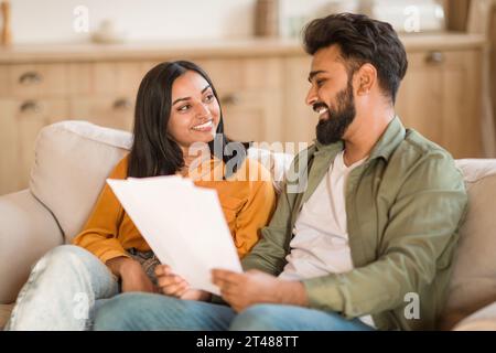 Young Hindu couple discussing papers on sofa at home Stock Photo