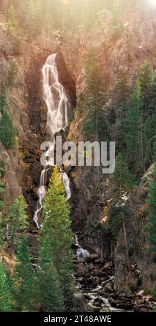 A long exposure photograph of Fish Creek Falls in Colorado with lots of evergreen trees and a bright spot just out of frame. Silky water and calming Stock Photo