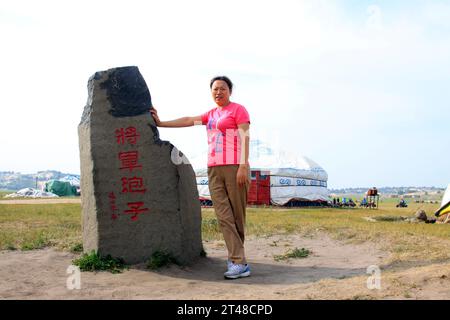 WULANBUTONG GRASSLAND - JULY 18: A female visitors standing beside stone tablet in the WuLanBuTong grassland, on July 18, 2014, Inner Mongolia autonom Stock Photo