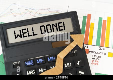 Business concept. On the business charts there is a calculator on the screen with the inscription - WELL DONE Stock Photo