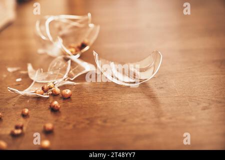 Close-up of a broken transparent glass of compote with raisins. Pieces of broken glass lie on the floor with space to copy. High quality photo Stock Photo