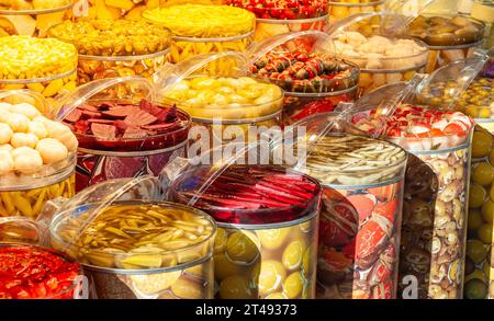 Large glass jars with different coloured pickled vegetables, such as beetroot, garlic, peppers. Stock Photo