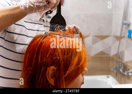 Profile of a pretty teenage girl coloring her hair red. The process of dyeing hair red. Style and modern fashion Stock Photo