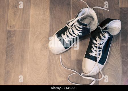 Top view of high black stylish sneakers with rubber soles and long untied laces. Casual fashionable classic hipster youth shoes. Stock Photo