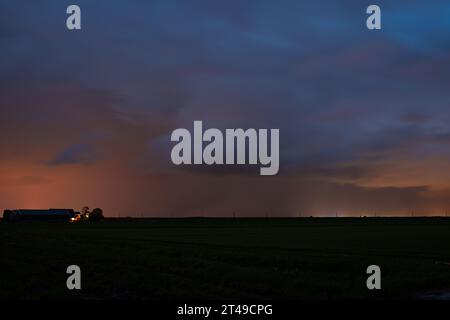 Thundery shower over farmland in the evening light Stock Photo