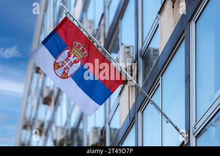 Serbian National Flag stretched on a flagpole placed on the facade of an administrative building. Stock Photo