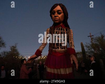 Tucson, Arizona, USA. 28th Oct, 2023. A determined Little Amal, the 12 foot puppet of a 10 year-old Syrian refugee girl, makes her way up Tumamoc Hill at sunrise. The land is sacred to local indigenous tribes, who settled it more than 2000 years ago. Tumamoc is Tohono O'odham for regal horned lizard, the shape of the mountain. (Credit Image: © Sue Dorfman/ZUMA Press Wire) EDITORIAL USAGE ONLY! Not for Commercial USAGE! Stock Photo