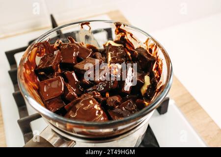 Chocolate and cocoa butter are melted by steaming in a glass plate placed on a saucepan with boiled water. Close-up, top view. Stock Photo