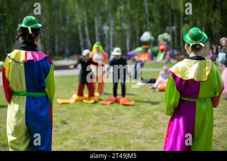 Children's party. Children's animators. Holding fun holiday on street. Clowns in park. Stock Photo