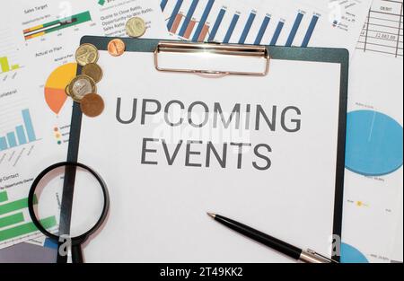 Text Upcoming Events written in notepad, Office desk with electronic devices, computer and paper, wood table from above, concept image for blog title Stock Photo