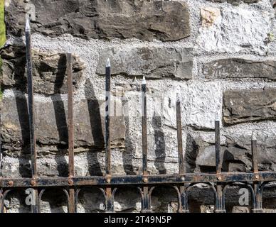 Wrought iron fence against a stone wall Stock Photo